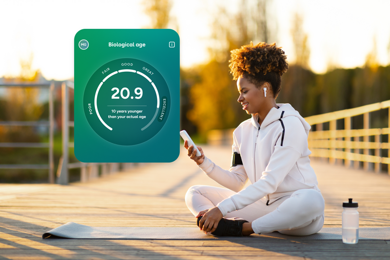 Lady sitting on wooden decking in sports outfit looking at phone. A screen showing biological age is visible. 